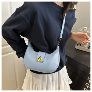 Detail view of light blue crescent bag featuring golden triangle buckle and leather strap