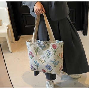Detailed texture of a large floral canvas tote bag showing the vintage embroidery