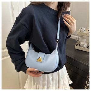 Detail of light blue crescent shoulder bag with golden triangle buckle on model