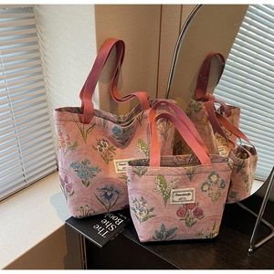 Detail of two-piece floral jacquard tote bags with pink handles in a home setting
