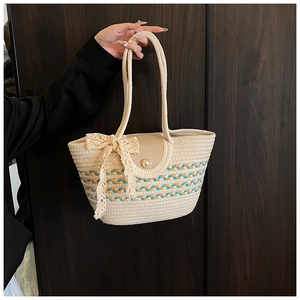 Detail of woven straw tote bag featuring blue orange wave pattern and pearl button closure