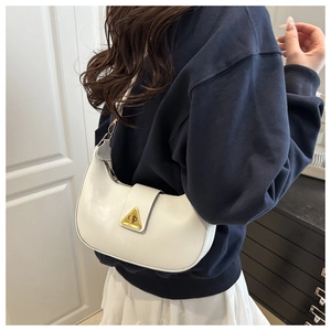 Close-up of white crescent shoulder bag with golden triangle buckle worn by a model