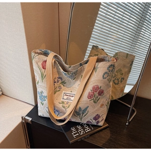 Close-up of floral embroidery texture and woven label on a large canvas tote bag