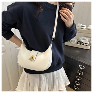 Close-up of white crescent shoulder bag with golden triangle clasp on model