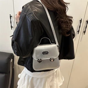 Sac bandoulière argenté métallisé avec double serrure porté par un mannequin