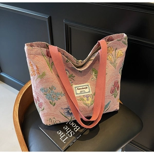 Detail view of large canvas tote bag featuring floral embroidery and pink wide shoulder straps