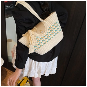 Detail of woven straw tote with pearl buckle and large lace bow on a beige shoulder bag