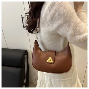 Detail of a brown crescent hobo bag showing a golden triangular buckle and zip closure