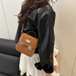 Sacoche rétro marron avec boucles argentées et poignée portée par un mannequin
