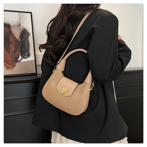 Detailed close-up of woven texture and golden square twist lock on beige dumpling handbag