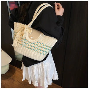 Detail of hand-woven straw tote with blue stripes, lace bow, and pearl closure