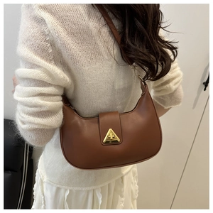 Detail showing vintage brown crescent underarm bag with gold triangular buckle on white sweater
