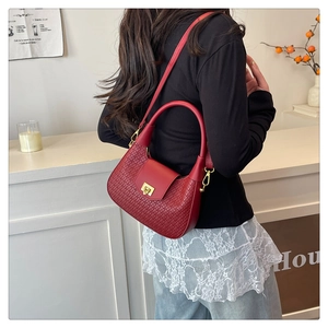 Detail of red woven dumpling bag featuring a golden metal lock and detachable chain strap