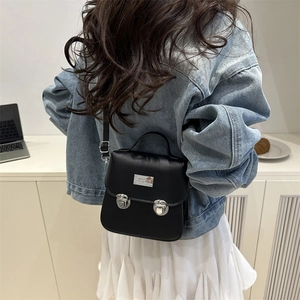 Sac à bandoulière vintage noir avec doubles boucles argentées porté par un mannequin
