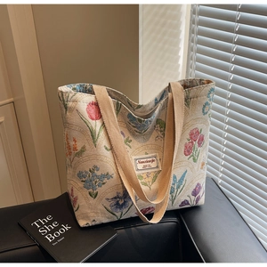 Close-up of floral embroidery detail on vintage canvas tote bag with woven handles