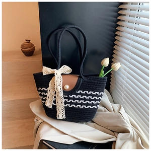 Detail of woven straw tote with black and white stripes, leather flap, and pearl buckle