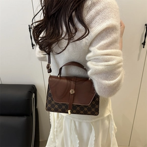 Brown vintage flap crossbody bag with monogram pattern and gold lock shown on shoulder