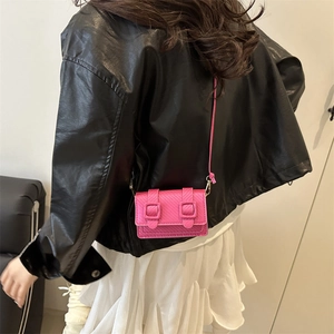 Pink mini crossbody bag with embossed texture shown on a female model in side view