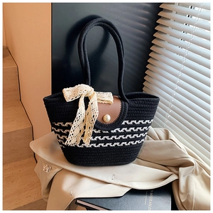 Detail of woven straw tote bag with black and white stripes and a lace bow detail