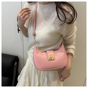 Detailed shot of pink crescent shoulder bag with golden triangle clasp on model