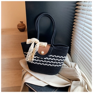 Detail of hand-woven tote bag with leather flap, pearl clasp and lace bow decoration