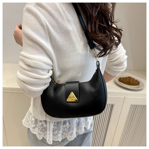Detail of black crescent shoulder bag featuring a gold triangular buckle on the leather strap