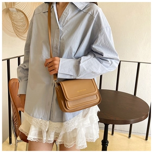 Détail d'un sac bandoulière en cuir PU marron avec rabat et texte FASHION & BAGS