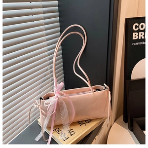 Detail view of the pink underarm bag featuring white lace bows and satin ribbon accents
