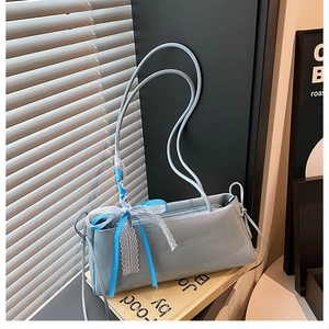 Detail of light blue baguette bag featuring delicate lace ribbon bow and glossy leather