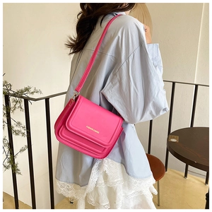 Détail du sac bandoulière en cuir magenta avec texte doré et fine bandoulière réglable
