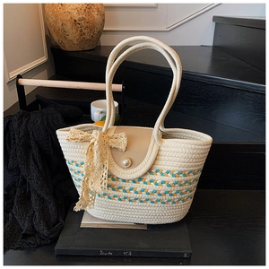 Detailed close-up of woven tote bag with orange stripes and elegant lace bow decoration