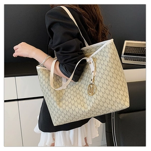 Detail of white tote bag featuring grey M-pattern monogram and gold logo pendant