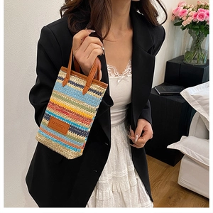 Detailed macro view of colorful striped woven phone bag with brown leather handles