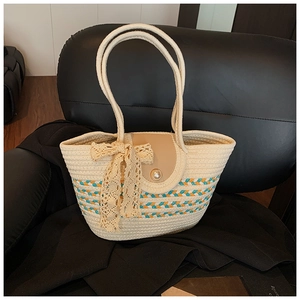 Detail of woven straw tote bag with lace bow, pearl buckle and blue orange stripes