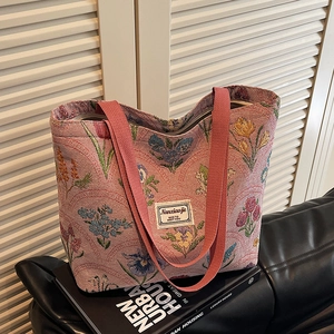 Floral knit tote bag with large capacity and pink straps on a leather sofa