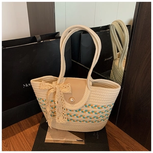 Detailed close-up of woven straw tote bag with lace bow and faux pearl buckle detail