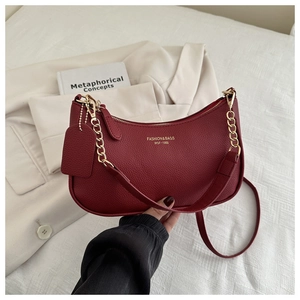 Detail of burgundy pebbled leather crescent bag with gold chain and printed logo
