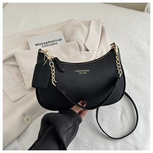Detail of black pebbled leather texture and gold chain on the crescent underarm bag