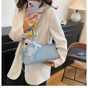 Close-up of light blue rectangle underarm bag with decorative lace bow and ribbon detail