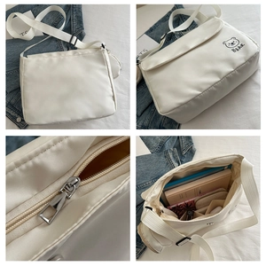 Detail view of white messenger bag featuring a bear print and adjustable fabric shoulder strap