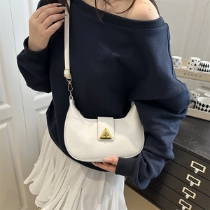 Chic white crescent shoulder bag with golden triangle clasp shown on a female model