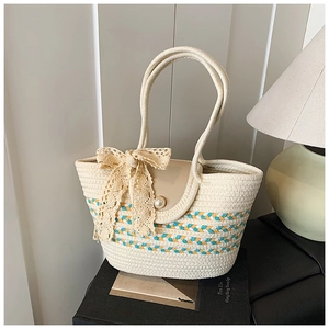 Detail of woven straw tote bag featuring a large lace bow and elegant pearl buckle closure