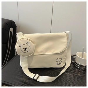 Detail view of beige canvas messenger bag with adjustable strap and cute bear coin purse