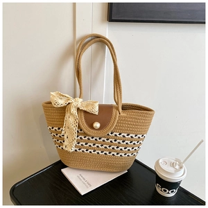 Detail of woven straw tote bag with black geometric patterns and faux pearl closure