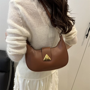 Brown leather crescent shoulder bag with vintage gold buckle on a model wearing white knitwear