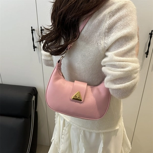 Pink crescent shoulder bag with golden triangle clasp shown on a model outfit