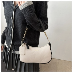 Detail of off-white pebbled leather shoulder bag with gold chain strap on model
