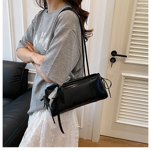 Side view of black glossy shoulder bag featuring white lace trim and ribbon bow accents