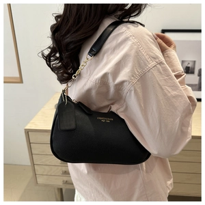 Detail of black pebbled leather underarm bag with gold chain strap and fashion text
