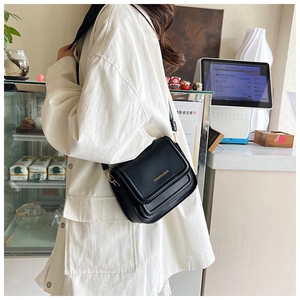 Détail d'un sac bandoulière noir avec lettrage doré et boucle métallique élégante